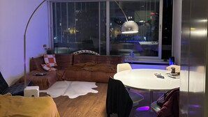 Ein modernes Wohnzimmer mit einem Ledersofa, einem weißen runden Tisch und einem großen Fenster.