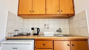 Eine Küche mit Holzausstattung, einem weißen Kühlschrank, einer Kaffeemaschine, einem Wasserkocher und einem Spülbecken.