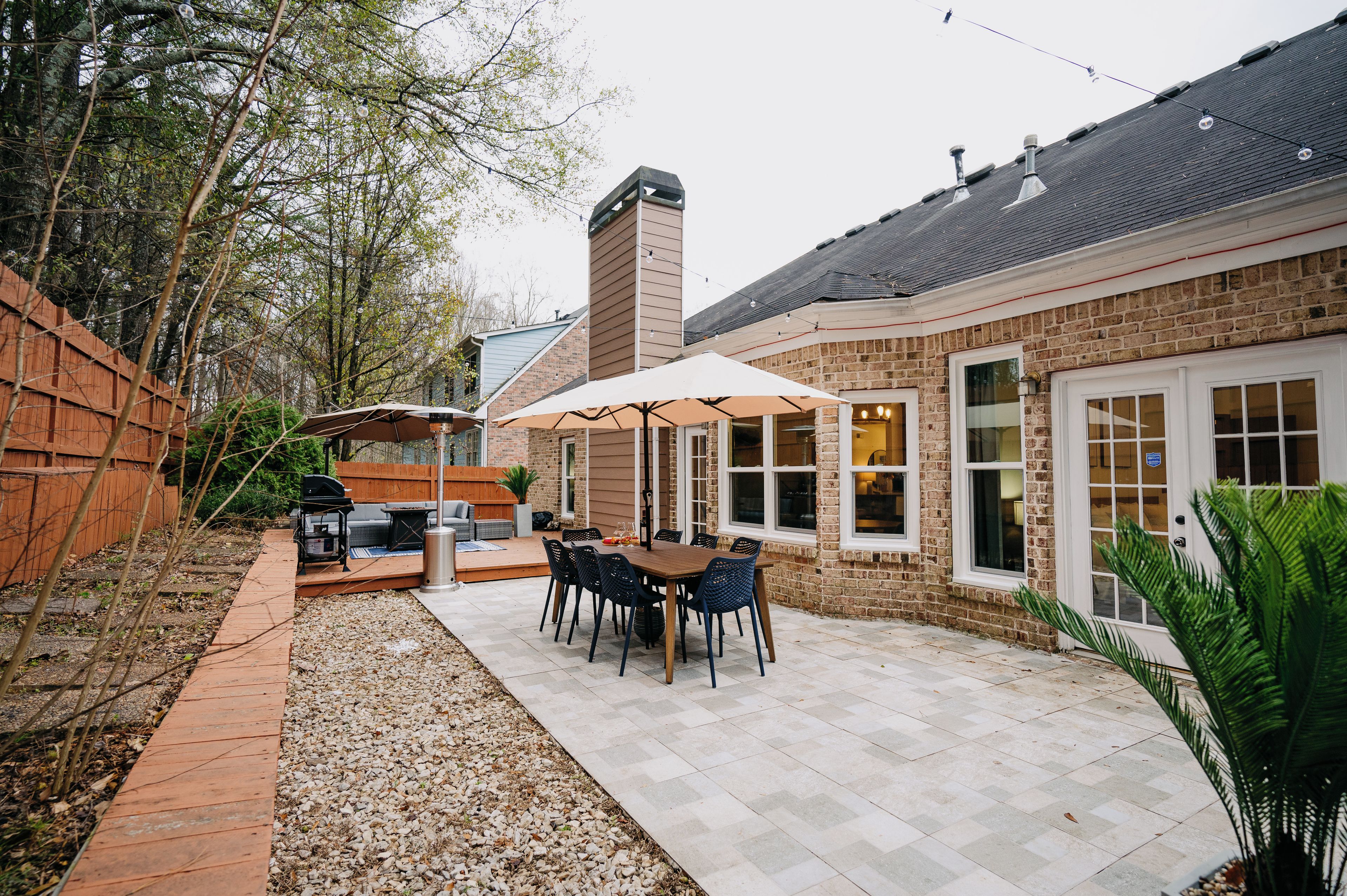 A patio area with a table and chairs, a barbecue grill, and a brick wall.