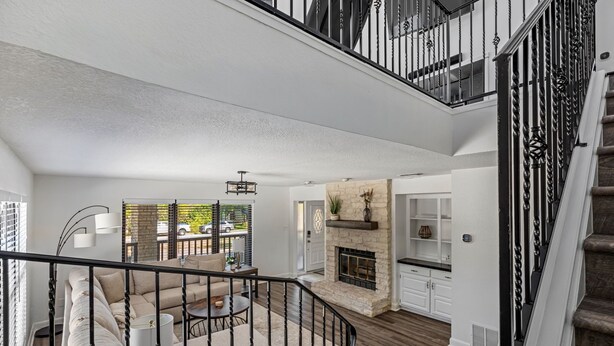Un vaste espace de vie doté d’une cheminée, d’un escalier et d’un balcon aménagé avec des sièges d’extérieur.