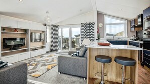 A modern kitchen with a large island, bar stools, and a view to the outside. - Laburnum, Tresaith - Two Bedroom Cottage, Sleeps 4 (Tresaith)