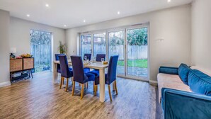 Un amplio espacio de sala con una mesa de comedor, sillas y un sofá azul.