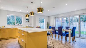 Una cocina moderna con una isla central, suelo de madera y grandes ventanales.
