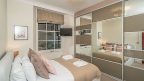 Una camera da letto con un letto, una televisione, una finestra con vista e una porta scorrevole per l'armadio.