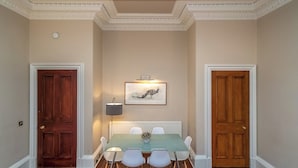 Una sala da pranzo con tavolo, sedie, un quadro incorniciato e due porte in legno.