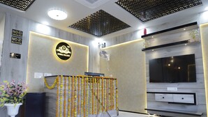 A reception area with a marble counter, a TV mounted on the wall, and a ceiling with a geometric pattern. - INDRA PALACE UNIT 2 (Jaipur)