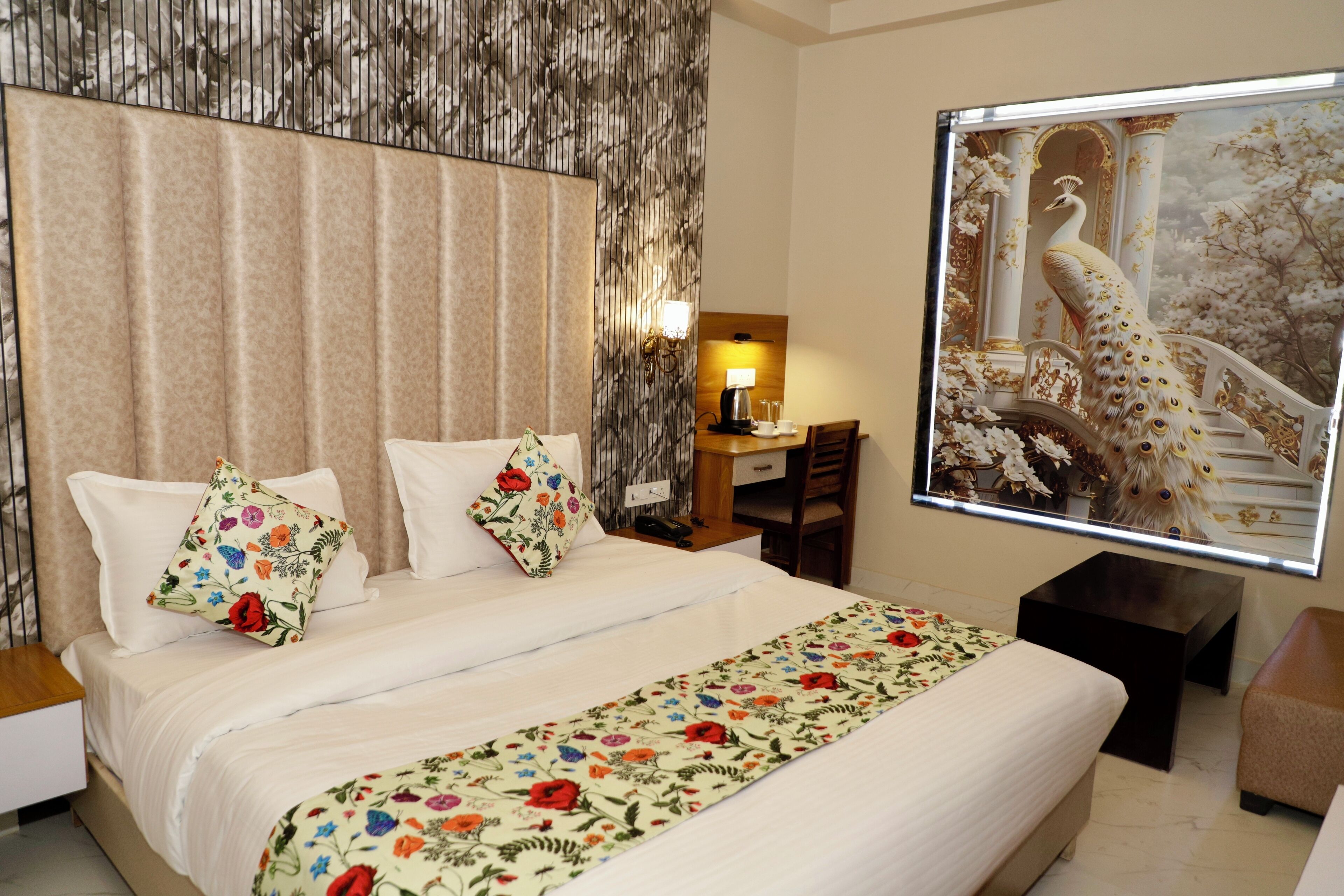 A hotel room with a large bed, a nightstand, a desk, and a wall-mounted TV.
