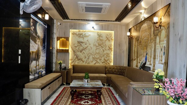 A modern living room with a beige sofa, a patterned rug, and a decorative wall panel. - INDRA PALACE UNIT 2 (Jaipur)