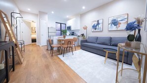Un salon moderne avec un canapé gris, un plancher en bois et un coin repas comprenant une table et des chaises.