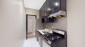 A kitchen with dark cabinets, a stainless steel refrigerator, a gas stove, and a tiled backsplash. - Spacious 4BR/2BA duplex apt w/ private patio, W/D (New York)