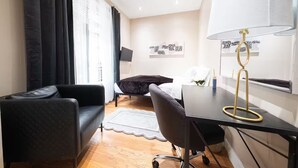 A modern hotel room with a black leather sofa, a desk with a lamp, a bed with a white comforter, and artwork on the walls. - Spacious 4BR/2BA duplex apt w/ private patio, W/D (New York)