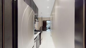 A modern kitchen with stainless steel appliances, black cabinets, and a white tiled floor. - Spacious 4BR/2BA duplex apt w/ private patio, W/D (New York)