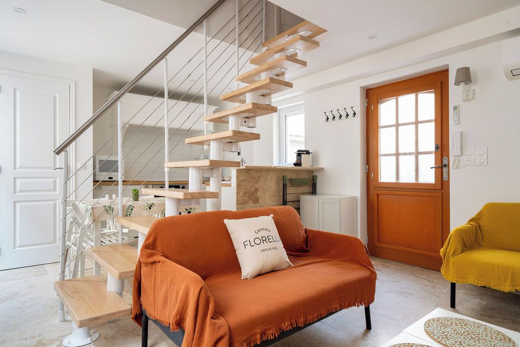 Ein modernes Wohnzimmer mit Treppe, einer Couch mit Kissen, einem gelben Sessel und einem Holztisch.