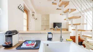 Een moderne keuken met een inbouwspoelbak, een koffieapparaat en een televisie op de achtergrond.