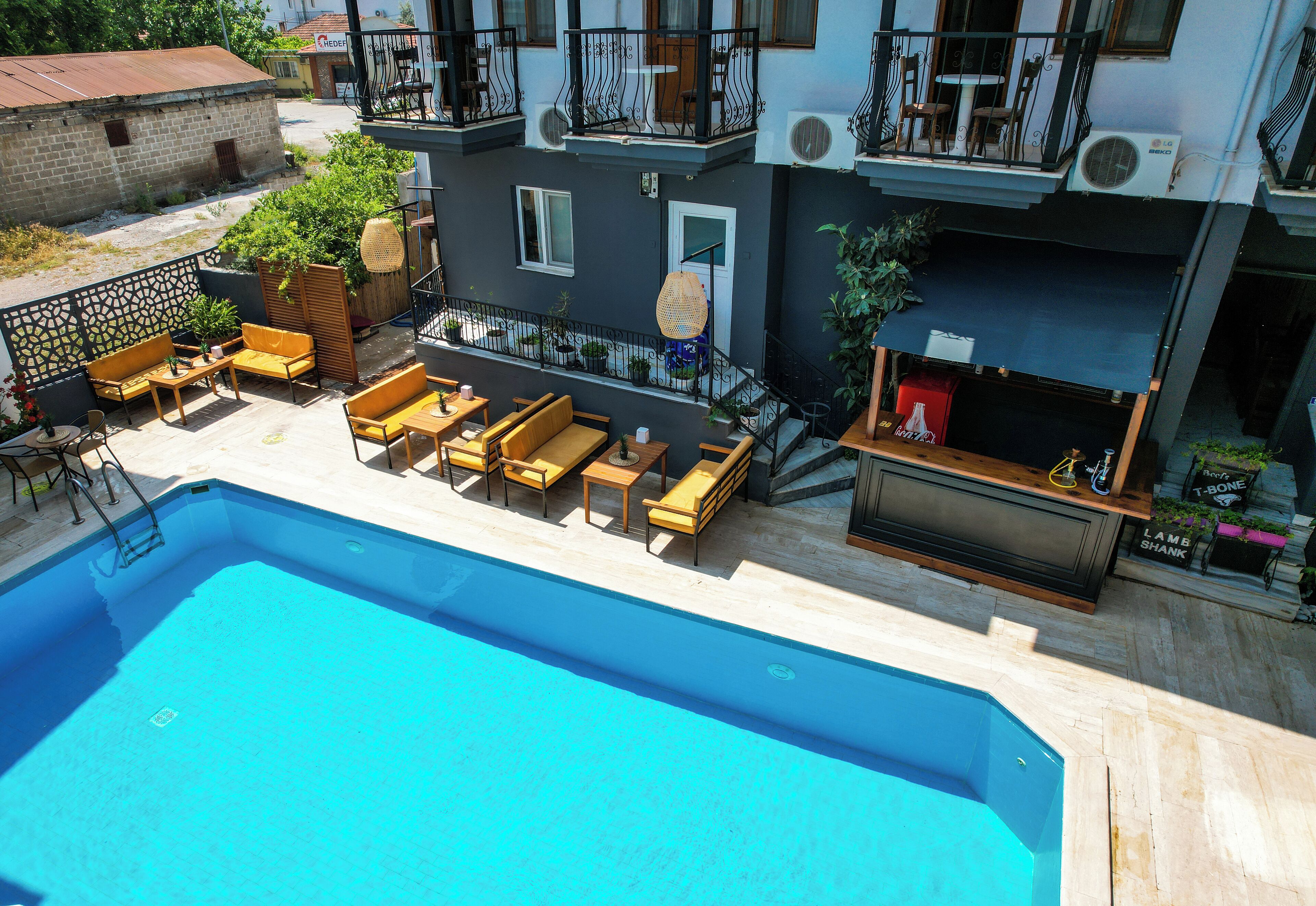 Uma área de piscina no terraço com espreguiçadeiras, um bar e vista para os edifícios ao redor.