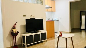 Un soggiorno con TV su un mobile bianco, un tavolino e una figura decorativa.