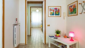Un passadís amb un radiador, una taula amb una làmpada i dos quadres florals emmarcades a la paret.
