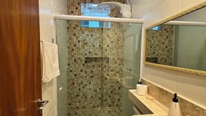 A modern bathroom with a glass-enclosed shower, a toilet, and a vanity with a mirror. - Quiet house - close to Vitória airport (Vitória)