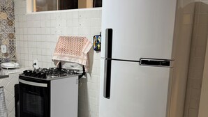 A kitchen with a white refrigerator, a stove, and a tiled backsplash. - Quiet house - close to Vitória airport (Vitória)