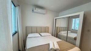 A hotel room with a bed, a window, an air conditioning unit, and a mirror. - Quiet house - close to Vitória airport (Vitória)