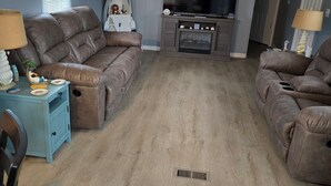 Un salon avec deux canapés en cuir marron, une table d’appoint bleue, une cheminée et un ventilateur de plafond.