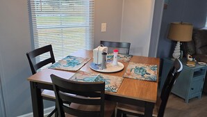 Un coin repas avec une table en bois, quatre chaises et un luminaire suspendu.