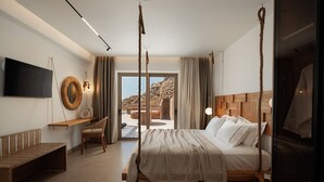 Een moderne slaapkamer met een groot bed, een televisie, een houten bankje en uitzicht op de omgeving.