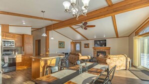 A spacious living area with a fireplace, a dining table, and a kitchen with wooden cabinets and a built-in oven.