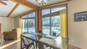 A dining area with a table and chairs, large windows, and a view of a snowy landscape.