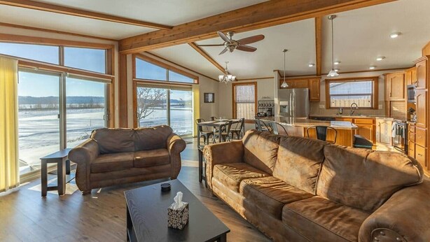 A spacious living room with a large sofa, a coffee table, and a view of a snowy landscape through large windows.