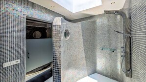 A modern bathroom with mosaic tile walls, a skylight, and a shower area. - Villa Puerto Calero Marina | Short Walk to Centre | Private Heated Pool (Lanzarote)