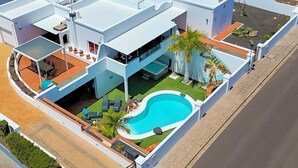 A modern multi-story building with a swimming pool, outdoor seating, and a well-maintained garden. - Villa Puerto Calero Marina | Short Walk to Centre | Private Heated Pool (Lanzarote)