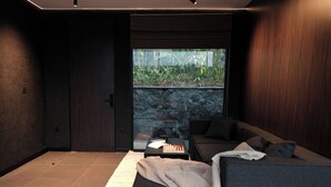 Un salon moderne avec un canapé, un jeu d’échecs et une vue sur la verdure, visible à travers une porte vitrée.