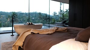 Une chambre moderne dotée d’un grand lit, d’une baignoire et offrant une vue sur un paysage luxuriant.