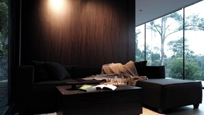 Un salon moderne avec un mur recouvert de panneaux en bois foncé, un canapé, une table basse avec des livres et une grande fenêtre donnant sur des arbres.