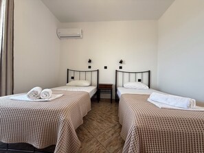 A twin room with two beds, a small table, and an air conditioning unit. - Ostria SeaView Suite (Kos)