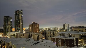 Un paisaje urbano al anochecer con rascacielos, tejados cubiertos de nieve y un cielo despejado.