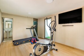 Ein Fitnessraum mit Laufband, Crosstrainer und Kurzhanteln.