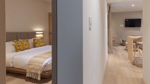 Et moderne hotelværelse med seng, sengebord og skriveområde med stol samt et fladskærms-tv.
