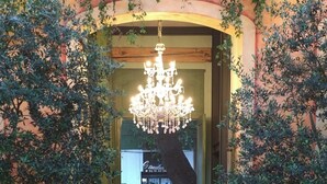 Una entrada con candelabro, plantas en macetas y un coche estacionado fuera.