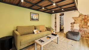 Un salón acogedor con un sofá verde, una mesita de centro y una pared de ladrillo.