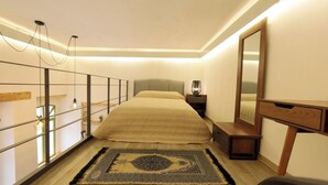 Un dormitorio con cama, mesita de noche, lámpara, espejo y un tapete decorativo.