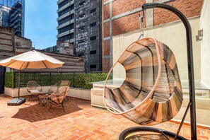 A rooftop patio with wicker chairs, a hanging chair, and a table under a large umbrella. - 304 Fabulous Apt near La Diana/Reforma/U.S Embassy (Mexico City)
