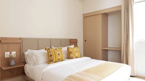 A neatly made bed with white linens and patterned pillows, a wooden nightstand with a vase of flowers, and a large wardrobe with a sliding door. - 101 Extraordinary apartment next to The St. Regis. Regis (Mexico City)