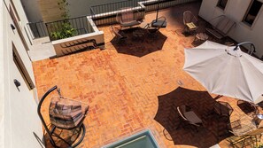 Une terrasse sur le toit avec un sol en briques disposées en motif de chevrons, des meubles d’extérieur et un grand parasol.