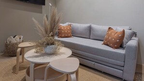 A modern living room with a grey sofa, two round tables, and a large TV mounted on the wall. - 101 Extraordinary apartment next to The St. Regis. Regis (Mexico City)