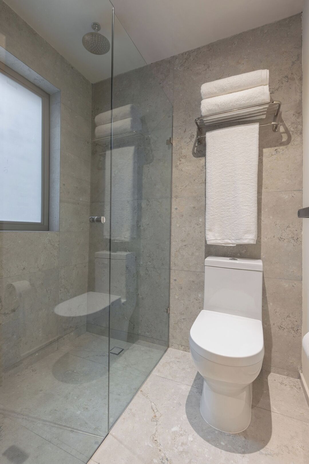 Et badeværelse med bruseniche, toilet og håndklædestang.
