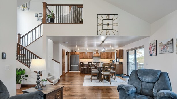 A spacious living area with a staircase, wooden flooring, a dining area with a central island, and a kitchen with wooden cabinets. - Sturgis Motorcycle Rally Rental - 5 bedroom with garage (Spearfish)