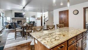 A spacious living area with a large wooden dining table, comfortable seating, and a kitchen with granite countertops. - Sturgis Motorcycle Rally Rental - 5 bedroom with garage (Spearfish)