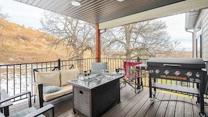 A covered deck with outdoor furniture, a grill, and a view of a hilly landscape. - Sturgis Motorcycle Rally Rental - 5 bedroom with garage (Spearfish)